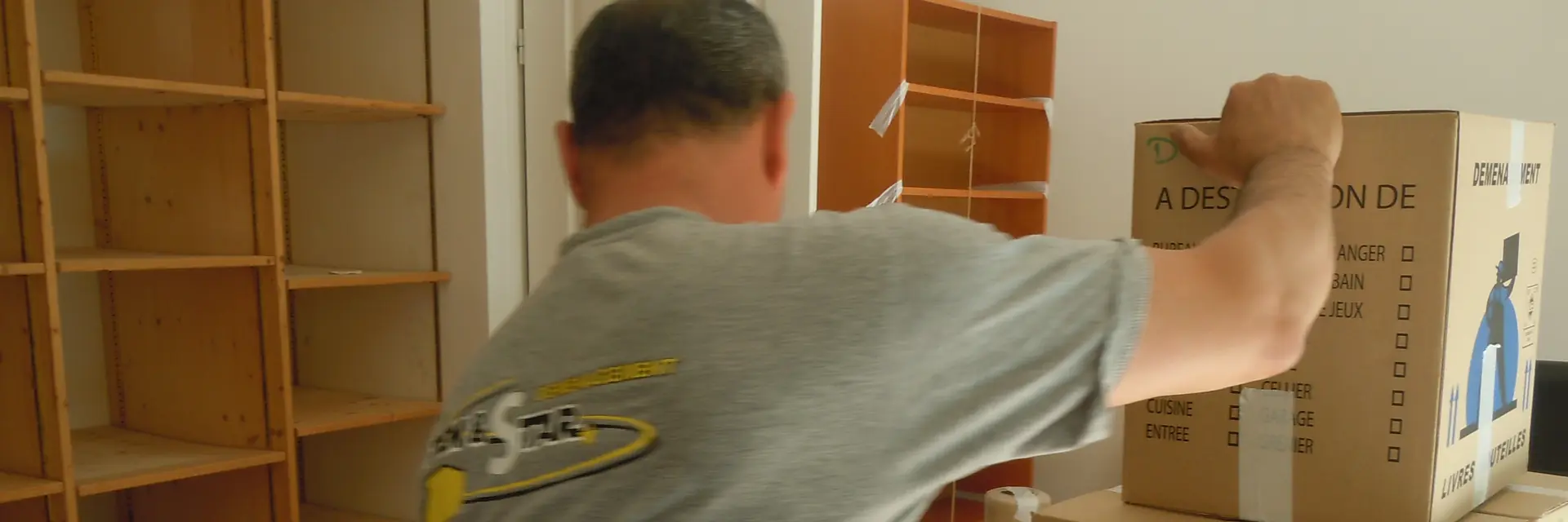 Déménageur MOVING DEMESTAR empilant des cartons chez un particulier